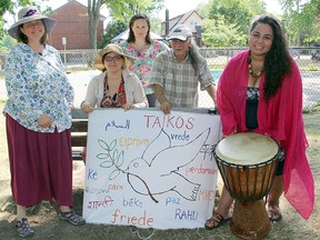 Wendy Perkins, left, Jolene Simko, Willa Thayer, George Biro, and Yessica Rivera Belsham, all members of the Hiroshima Day Coalition, gather in McBurney Park toting a sign with