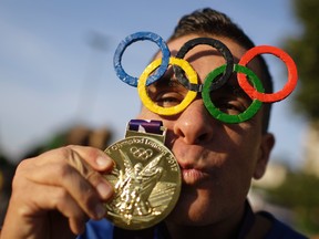 A man poses for a picture wearing Olympic rings glasses and kissing a medal before entering the Maracana Stadium ahead of the opening ceremony for the 2016 Summer Olympics in Rio de Janeiro, Brazil, Friday, Aug. 5, 2016. (AP Photo/Natacha Pisarenko)