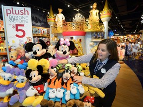 Laurie Baker, manager of the new Disney store in Masonville Mall, puts the final touches on their displays.  (MORRIS LAMONT, The London Free Press)