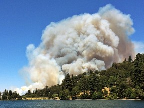 Heavy smoke looms up over Lake Gregory and mountaintop homes in Crestline, Calif., as a wildfire threatens the San Bernardino Mountains village about 55 miles east of Los Angeles Sunday, Aug. 7, 2016. A massive plume of smoke could be seen blowing north toward the Mojave Desert.  (Rachel Luna/The Sun via AP)