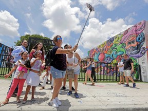A family from Peru takes a selfie in front of the Wynwood Walls, Friday, Aug. 5, 2016, in the Wynwood area of Miami. The recent announcement that more than a dozen people have been infected with Zika by mosquitoes in the area has scared away some, but many others are still coming. (AP Photo/Alan Diaz)