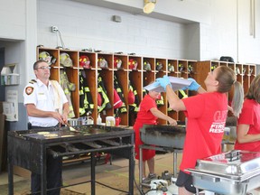 Goderich fire captain, Jeff Wormingston tosses pancakes in the air while Teri St. Louis catches them. (Laura Broadley/Goderich Signal Star)