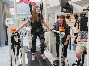 Robotic gait training can replace traditional physical therapy for helping improve the walking abilities of kids with cerebral palsy. Maggie Slessor, 12-year-old with cerebral palsy, demonstrated the Lokomat at the Glenrose Rehabilitation hospital on August 9, 2016. Maggie shares a laugh with Kelsey Switzer, physio therapist. Photo by Shaughn Butts / Postmedia