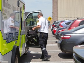 A paramedic carries a child?s car seat into an ambulance after the car it was in crashed into an emergency exit door Tuesday at Costco in north London. (CRAIG GLOVER, The London Free Press)