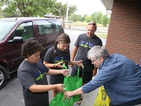 Jason Miller/The Intelligencer
Brenda Rump donated non-perishable food items to Ethan Henriquez and Rachel Stephens, while pastor Mark Hymus looks on. Ethan and Rachel are a part of the Go Make A Difference program, operated at Parkdale Baptist Church, geared toward giving back to the community by doing things like collecting food items for Gleaners Food Bank.
