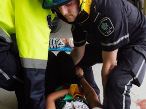 Luke Hendry/Intelligencer file photo
Loyalist College paramedic student Pawel Nowak raises his hands as paramedics Brenda Murray, Jordan Richter and Sara Johansen (behind Nowak) fasten him to a back board while training in Belleville, May 28, 2013. Hastings-Quinte paramedics may soon take part in a study examining the need for such extensive immobilization of all trauma patients.