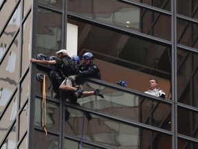 New York Police officers struggle as they pull a man through a window as he scaled the east side of Trump Tower using suction cups, Wednesday, Aug. 10, 2016, in New York. A police spokeswoman says officers responded to Donald Trump's namesake skyscraper on Fifth Avenue in Manhattan but had no further information. The 58-story building is headquarters to the Republican presidential nominee's campaign. He also lives there. (AP Photo/Julie Jacobson)