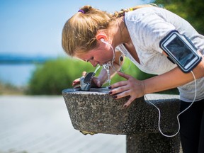 Jane Burakova tries get some relief from the heat from a water fountain along the Martin Goodman Trail near the Humber River in Toronto Wednesday August 10, 2016. (Ernest Doroszuk/Toronto Sun)
