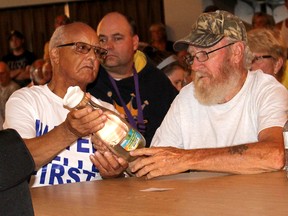 Chatham Township residents Bernie Simmons, left, and Wayne Blue, look at sand that is regularly showint up in the well water from a property in Dover Township, which is believed to be caused from the vibration of a nearby industrial turbine. They were among the more than 200 people that attended a public meeting held by the citizen's group Water Wells First at Country View Golf Course  in Oungah, Ont. on Wednesday August 10, 2016. (Ellwood Shreve/Chatham Daily News/Postmedia Network)