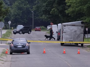 A police officer and his canine partner walk across Park Street near the house where Aaron Driver was shot by RCMP officers Wednesday night. (CRAIG GLOVER, The London Free Press)