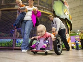 Evelyn Moore isn't the fastest kid on the racetrack, but she's by far the tiniest. At 13-months old, the paralyzed toddler skilfully wheels her homemade wheelchair around the simulated track at Treehouse, an indoor playground in northeast Edmonton that she often visits with her mom.