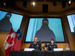 Video footage showing Aaron Driver is seen behind RCMP Deputy Commissioner Mike Cabana (left) and Assistant Commissioner Jennifer Strachan during a press conference for what the RCMP are calling a terrorism incident, in Strathroy, Ontario yesterday, on Thursday, Aug. 11, 2016 in Ottawa. THE CANADIAN PRESS/Justin Tang