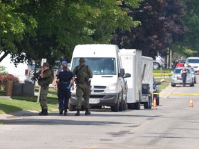 An OPP officer glances back as he and a group of colleagues walk away Thursday from 212 Park St., where terror suspect Aaron Driver was shot and killed by police in Strathroy a day earlier. (CRAIG GLOVER, The London Free Press)