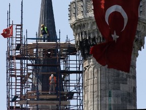 Two men on scaffolding work at the Sultan Ahmed Mosque's minaret, also known as Blue Mosque, in Istanbul, Thursday, Aug. 11, 2016. The Turkish government launched a sweeping crackdown after the failed July 15th coup, targeting followers of a U.S.-based Muslim cleric Fethullah Gulen, whom it accuses of orchestrating the attempted putsch that left more than 270 dead. (AP Photo/Thanassis Stavrakis)