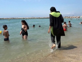 In this Aug. 4, 2016 file photo made from video, Nissrine Samali, 20, gets into the sea wearing traditional Islamic dress, in Marseille, southern France. The French resort of Cannes has banned full-body, head-covering swimsuits worn by some Muslim women from its beaches, citing security concerns. A City Hall official said the ordinance, in effect for August, could apply to burkini-style swimsuits. (AP Photo, File)