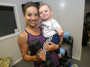 Fitness instructor Ainsley McSorley poses in her home gym, with her son Zayd. McSorely is now teaching fitness classes, in her home, to new moms.