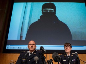 Video footage showing Aaron Driver is seen behind RCMP Deputy Commissioner Mike Cabana (left) and Assistant Commissioner Jennifer Strachan during a press conference for what the RCMP are calling a terrorism incident, in Strathroy, Ontario yesterday, on Thursday, Aug. 11, 2016 in Ottawa. (THE CANADIAN PRESS/Justin Tang)