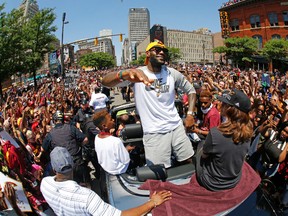 Cleveland Cavaliers' LeBron James, center, stands in the back of a Rolls-Royce as it makes it way through the crowd during a parade in downtown Cleveland celebrating the team's NBA championship. (AP Photo/Gene J. Puskar)