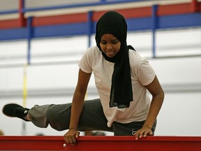 Fatuma Gelle (17-years-old) climbs over a fence during a police training obstacle course at police headquarters in downtown Edmonton on Friday August 12, 2016. LARRY WONG/Postmedia