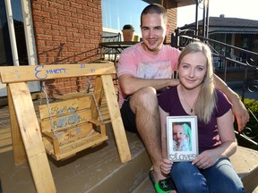 Ashley Lisabeth and Frank Greco show a picture of their son Emmett who died one year ago from myocarditis. The swing was made by a friend of the family for their memory garden. They will be hosting a walk to remember Emmett and raise awareness about myocarditis this weekend. (MORRIS LAMONT/The London Free Press/Postmedia Network)