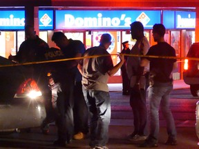 A group of people stand outside a pizza place on Wexford Rd. in Brampton where a man was shot late on Aug. 12, 2016. It was one of three shootings in the GTA overnight. (Pascal Marchand/Special to the Toronto Sun)