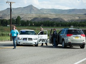 Police officers and state employees prevent drivers from entering Hatch, N.M., after a shooting on Friday, Aug. 12, 2016. Dona Ana County authorities say a Hatch police officer has died after being shot during a traffic stop on Friday. (Anayssa Vasquez/The Las Cruces Sun-News via AP)