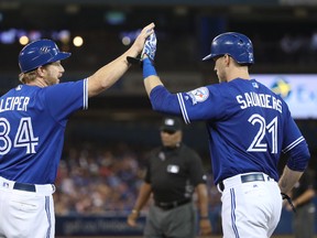 Michael Saunders of the Toronto Blue Jays is congratulated by first base coach Tim Leiper after hitting a bunt single in the sixth inning during MLB game action against the Houston Astros on August 13, 2016 at Rogers Centre in Toronto, Ontario, Canada. (Photo by Tom Szczerbowski/Getty Images)