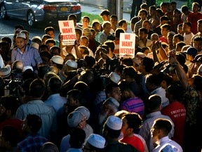 People gather for a demonstration Saturday, Aug. 13, 2016, near a crime scene after an imam and his friend were fatally shot while walking home from a mosque. Police said 55-year-old Imam Maulama Akonjee and his 64-year-old associate, Tharam Uddin, were shot in the back of the head as they left the Al-Furqan Jame Masjid mosque in the Ozone Park section of Queens. (AP Photo/Craig Ruttle)