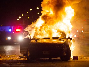 A car burns as a crowd of more than 100 people gathers following the fatal shooting of a man in Milwaukee, Saturday, Aug. 13, 2016. The Milwaukee Journal Sentinel reported that officers got in their cars to leave at one point, and some in the crowd started smashing a squad car's window, and another vehicle, pictured, was set on fire. The gathering occurred in the neighborhood where a Milwaukee officer shot and killed a man police say was armed hours earlier during a foot chase. (Calvin Mattheis/Milwaukee Journal-Sentinel via AP)