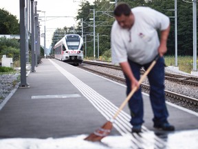 In this Aug. 13, 2016 picture, a man cleans the platform as the train stands at the station following an attack onboard, in Salez, Switzerland. A 34-year-old woman died Sunday from wounds suffered after a man attacked her and four others with a knife and a burning liquid aboard a crowded train in Switzerland. (Gian Ehrenzeller/Keystone via AP)
