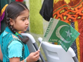 Fatima Khan waves her Pakistani flag at the Pakistan Independence Day celebrations in Kingston on Sunday. (Steph Crosier/The Whig-Standard)