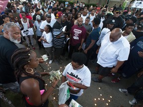 Kimberly Neal collects money at a gathering in memory of her brother, Sylville Smith, 23, where he was shot and killed Saturday in Milwaukee, Sunday, Aug. 14, 2016.  Police in Milwaukee say a black man whose killing by police touched off arson and rock-throwing was shot by a black officer after turning toward him with a gun in his hand. Six businesses were burned in the unrest that spilled past midnight Sunday. (Mark Hoffman/Milwaukee Journal-Sentinel via AP)
