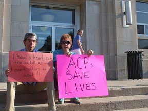 Matthew Lloyd and Ruthann Knight sit on the steps of the Huron County Courthouse as a part of a larger group protesting the elimination of the Advanced Care Paramedic program on Aug. 10. (Laura Broadley/Goderich Signal Star)