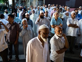 In this Saturday, Aug. 13, 2016, photo, people gather near a crime scene for a demonstration after the leader of a New York City mosque and an associate were fatally shot in a brazen daylight attack as they left afternoon prayers Saturday. Police said 55-year-old Imam Maulama Akonjee and his 64-year-old associate, Tharam Uddin, were shot in the back of the head as they left the Al-Furqan Jame Masjid mosque in the Ozone Park section of Queens shortly before 2 p.m. (AP Photo/Craig Ruttle)