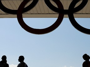 Fans walk to their seats under a set of Olympic rings before the artistic gymnastics men's apparatus final at the 2016 Summer Olympics in Rio de Janeiro, Brazil, Monday, Aug. 15, 2016. (AP Photo/Charlie Riedel)