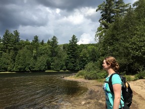 In this photo taken on Saturday, Aug. 6, 2016, Sarah Walsh, president of the trail committee for the A2A Collaborative in Lansdowne, Ontario, pauses at the shore of Rich Lake along a trail at the Adirondack Interpretive Center, where the 400-mile A2A Trail is proposed to begin. The nonprofit A2A Collaborative is planning a hiking trail from here to Algonquin Provincial Park following the general route taken by a radio-collared moose released by wildlife workers in the surrounding Huntington Wildlife Forest here in 1998. (AP Photo/Mary Esch)