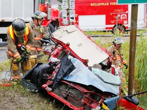 Luke Hendry/The Intelligencer
Thurlow volunteer firefighters use hydraulic equipment to cut away part of a Honda Civic damaged in a collision with a dump truck (background) in Roslin north of Belleville Tuesday. Firefighters and Hastings-Quinte paramedics had earlier freed the car's passenger, a woman in her early 20s. She suffered non-life-threatening injuries and was taken to hospital.