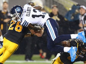 Kevin Elliott of the Toronto Argos is hit hard by Craig Butler of the Hamilton Tiger-Cats during CFL action at Tim Hortons Field in Hamilton Monday August 3, 2015. (Dave Abel/Toronto Sun/Postmedia Network)