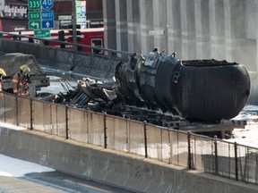 Firefighters stand next to a fuel tanker that burst into flames on autoroute 40 during rush hour after colliding with at least two other vehicles Tuesday, August 9, 2016 in Montreal. THE CANADIAN PRESS/Paul Chiasson