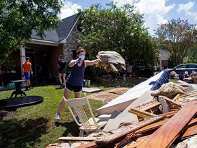 Hannah McLain, 22, a volunteer organized by a local Baton Rouge church, helps throw out waterlogged items from the home of Rhonda Brewer in Baton Rouge, La., Tuesday, Aug. 16, 2016. Around 100 students from LSU and local high schools also helped residents clean up in the area. At least 40,000 homes were damaged and eight people killed in the historic Louisiana floods, the governor said Tuesday, giving a stark assessment of the widespread disaster. (AP Photo/Max Becherer)