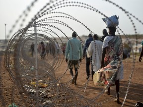 In this file photo taken Tuesday, Jan. 19, 2016, displaced people walk next to a razor wire fence at the United Nations base in the capital Juba, South Sudan. A UN report describing sweeping crimes like children and the disabled being burned alive and fighters being allowed to rape women as payment shows South Sudan is facing "one of the most horrendous human rights situations in the world," the UN human rights chief said Friday, March 11, 2016. (AP Photo/Jason Patinkin, File)