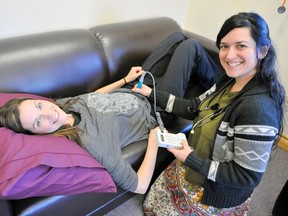 Kim Cleland (right) a registered midwife, shows how she listens for the heartbeat of a baby using midwife assistant Amy Hastings. (DANIEL R. PEARCE, Postmedia Network)