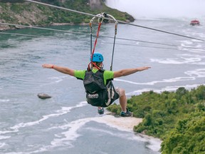 In this July 19, 2016 photo provided by WildPlay Ltd., a tourist suspended above the water from zip lines makes his way at speeds of up to 40 mph toward the the mist of the Horseshoe Falls, on the Ontario side of Niagara Falls. The overhead cables have evolved from a fun way to explore jungle canopies to trendy additions for long-established outdoor destinations. (Kien Tran/WildPlay Ltd. via AP)