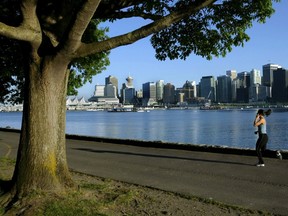 A jogger runs along the seawall in Stanley Park with the city skyline in the background in this file photo. Mayor Don Iveson is pushing for a river valley project similar to Vancouver's popular seawall.