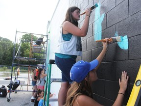 Janelle Hyde, in white, and Rain Morgan, both 14, are part of a Random Acts of Art Workshop, through the Judith and Norman Alix Art Gallery, painting a mural on the Kwik Kopy building at Front and Exmouth streets in Sarnia. The project, expected to wrap up Friday, is part of the gallery's Mural Madness program. (Tyler Kula/Sarnia Observer/Postmedia Network)