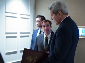 In this Oct. 23, 2015 file-pool photo, Secretary of State John Kerry, speaks to senior adviser John Kirby before a news conference in Vienna. The State Department says a $400 million cash payment to Iran was contingent on the release of American prisoners. Spokesman Kirby says negotiations over the U.S. returning Iranian money from a decades-old account was conducted separately from the prisoner talks. But he says the U.S. withheld delivery of the cash as leverage until the U.S. citizens had left Iran. (Carlo Allegri/Pool Photo via AP, File)