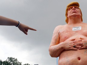 A woman points at a statue of a naked Republican presidential candidate Donald Trump, Thursday, Aug. 18, 2016 in New York's Union Square.  The statue was removed by New York City Department of Parks & Recreation employees. (AP Photo/Mary Altaffer)
