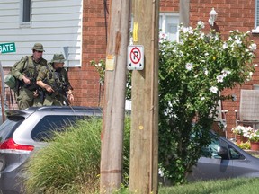 OPP officers carry rifles as they walk around the corner of a home at the corner of Park Street and Westgate Avenue, near a home at 212 Park Street where terrorism suspect Aaron Driver was shot and killed by police, in Strathroy. (CRAIG GLOVER, The London Free Press)