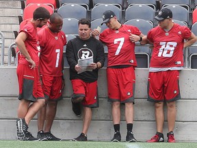 Redblacks quarterbacks do some homework on the sidelines at TD Place. (Tony Caldwell, Ottawa Sun)