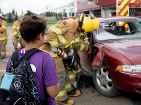 Firefighters tear open a car at a mock crash site to give tri-area students an idea of what it’s like at an actual motor vehicle collision, at the Living Waters school in Spruce Grove on Wednesday, Aug. 10, 2016. This demonstration was one of several during the the three-day Parkland Call to Duty Youth Camp. - Photo by Yasmin Mayne
